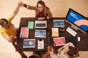 What is digital marketing? A team of professionals collaborating around a conference table with laptops, analytics reports, and digital marketing strategy materials, illustrating teamwork, online marketing, SEO, social media, and business growth.